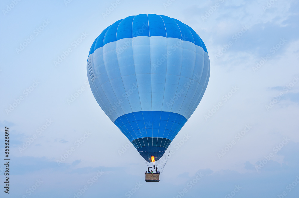 Naklejka premium Blue hot air balloon above the land at evening time.