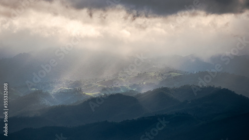 Fototapeta Naklejka Na Ścianę i Meble -  Rainy around but sun shine show up to beam through the clouds to the forest in the mountain on Doi Inthanon. Chiang Mai, Thailand.