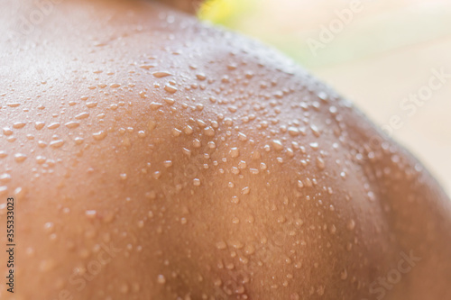 Drops of water caused by sweat due to the hot weather on the back plate of the young man.