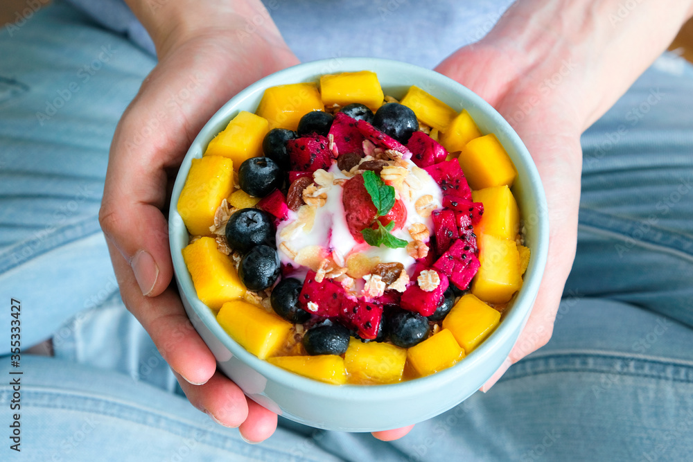 Hand of woman holding bowl of fresh Strawberry and Blueberry yogurt .Concept of healthy diet and weight control Hand of woman holding bowl of fresh Strawberry and Blueberry yogurt .Concept of healthy diet and weight control