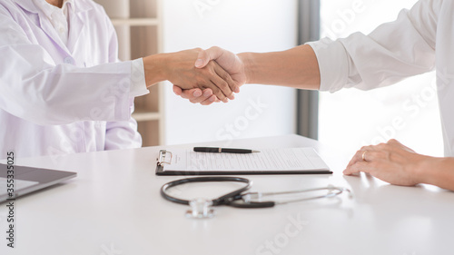 Attractive Doctor and patient shaking hands for encouragement and empathy, healthcare and assistance, Medical concept.