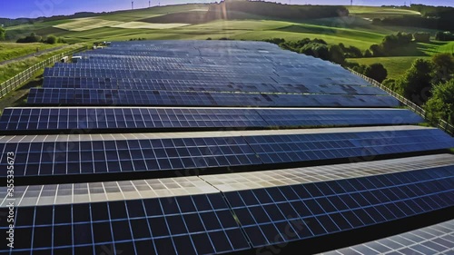 Aerial view of solar farm, sunset. Rows of modern photovoltaic solar panels. Renewable ecological source of energy from the sun.