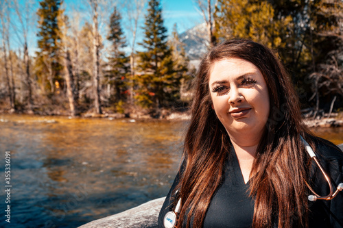 Woman nurse in black scrubs with a stethoscope in the mountains