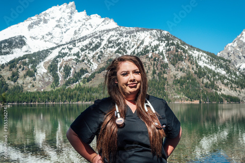 Woman nurse in black scrubs with a stethoscope in the mountains