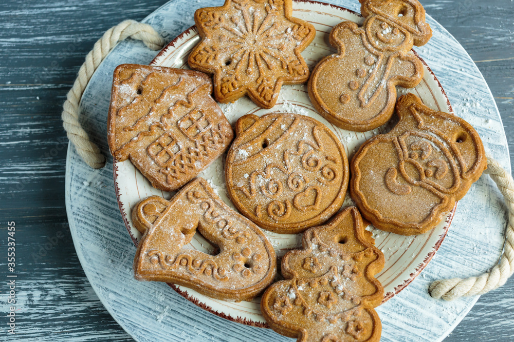 Homemade gingerbread cookies on tray with cup of coffee on grunge gray wooden background. Christmas and New Year celebration background. Close up of home baked cookies with icing.	