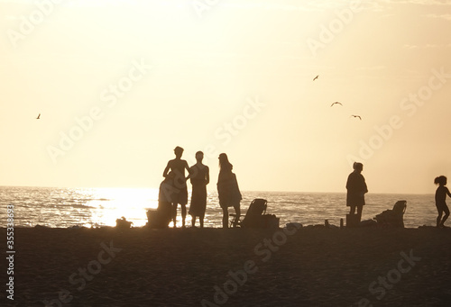 Silhouette of family enjoying the beach at sunset orange sky and seagulls