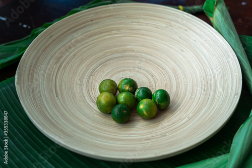 Fresh local calamansi or limau kasturi (citrus microcarpa) on a wooden plate. photo