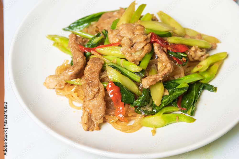 Stir-fried rice stick noodles in sweet soy sauce with pork, chili and chinese broccoli in white plate. Stir-fried rice stick noodles in sweet soy sauce with pork, chili and chinese broccoli in white plate.