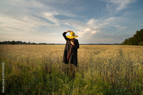 Surreal woman - scarecrow stands in weath cereal field. Concept of environment and identity.