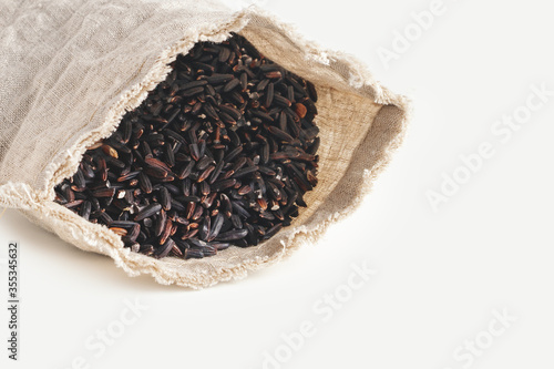 Black wild rice in pouch on white blank space. Close up.