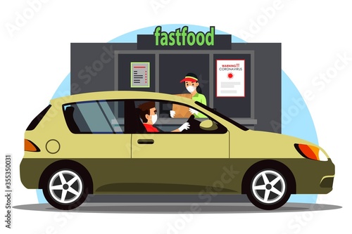 Masked driver in car takes fast food order at Drive Thru counter