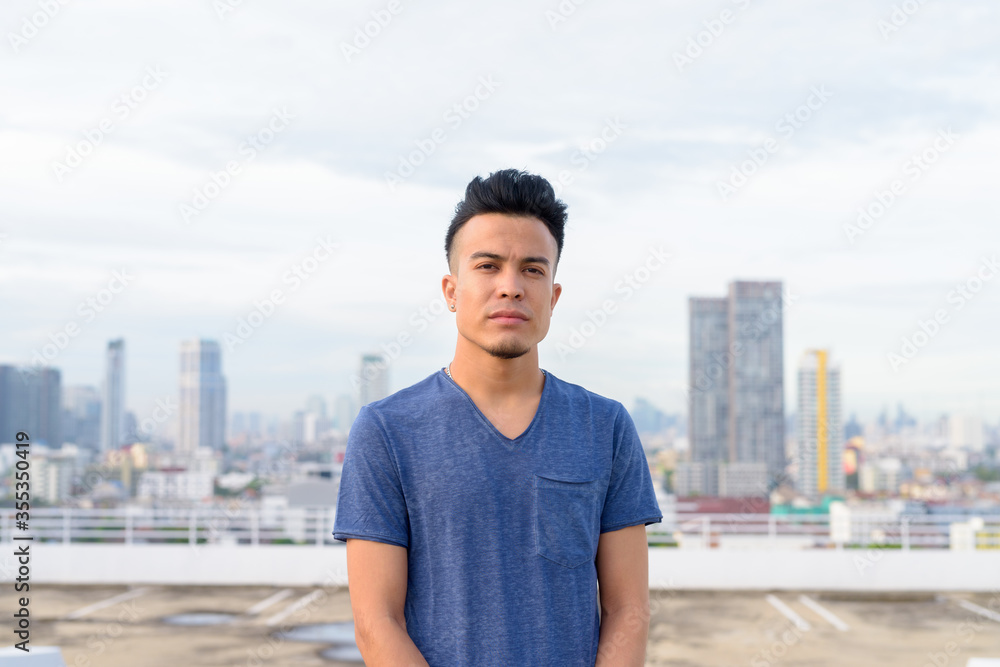Young handsome multi ethnic man against view of the city Young handsome multi ethnic man against view of the city