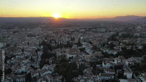 Aerial shot of houses in city against sky during sunset, drone flying backward over cityscape - Granada, Spain photo