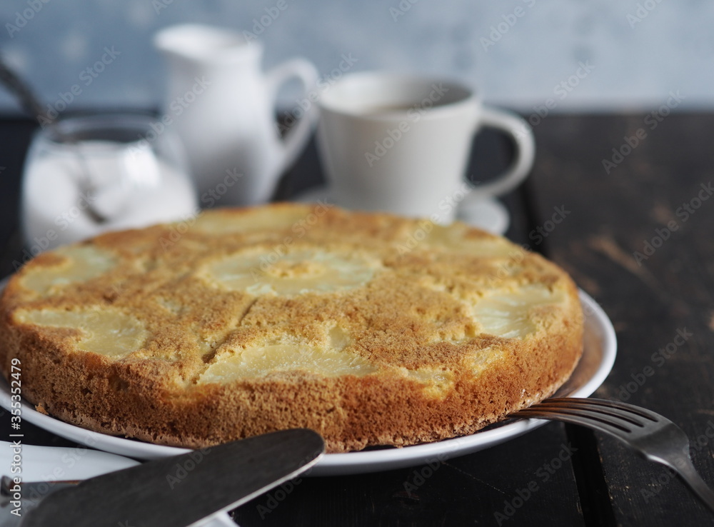 Sponge cake with pineapple on a dark wooden table.Home cooking. Sponge cake with pineapple on a dark wooden table.Home cooking.