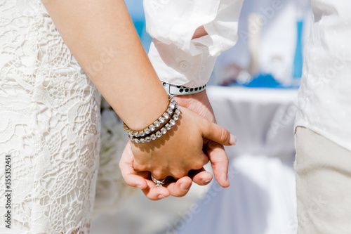 Newlyweds at the wedding romantic couple holding hands during destination wedding marriage matrimonial ceremony on the sandy beach in Dominican republic, Punta Cana. Family, love, unity concept. 