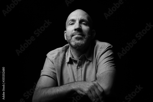 A beautiful and original portrait of a brutal man, guy, brunette, with stubble that emotionally poses on a dark or black background