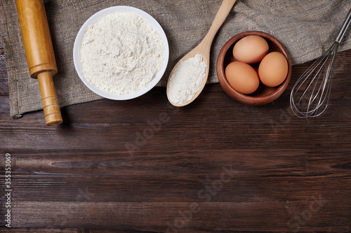 Flour and eggs on wooden table. Ingredients for baking.