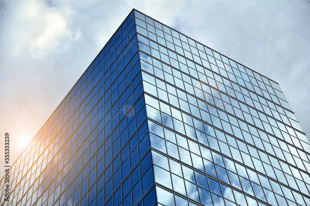 Facade texture of a glass mirrored office building. Fragment of the facade. Bottom view of modern skyscrapers in business district in evening light at sunset with lens flare filter effect. Facade texture of a glass mirrored office building. Fragment of the facade. Bottom view of modern skyscrapers in business district in evening light at sunset with lens flare filter effect.