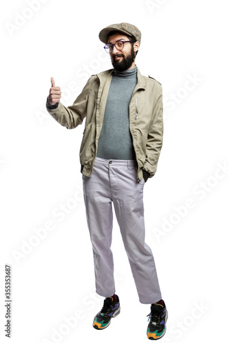 Stylish young man in glasses and with a beard holds a thumbs up. Isolated on a white background. Vertical.