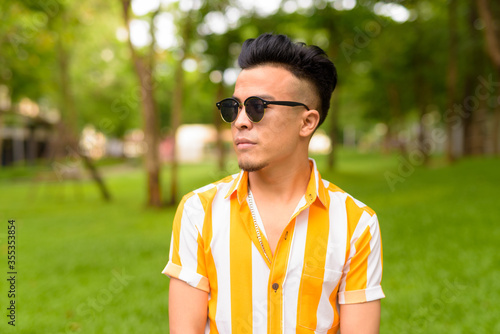 Young handsome multi ethnic man wearing sunglasses at the park outdoors