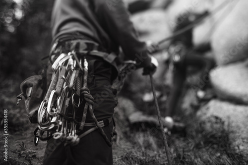 Climbing equipment, hardware and tools on the climber's harness, during training with a partner, close-up, black and white.