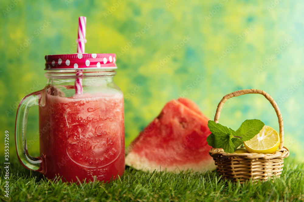 Watermelon juice in a jar with watermelon pieces and lemon wedge and mint leaves in a basket Watermelon juice in a jar with watermelon pieces and lemon wedge and mint leaves in a basket