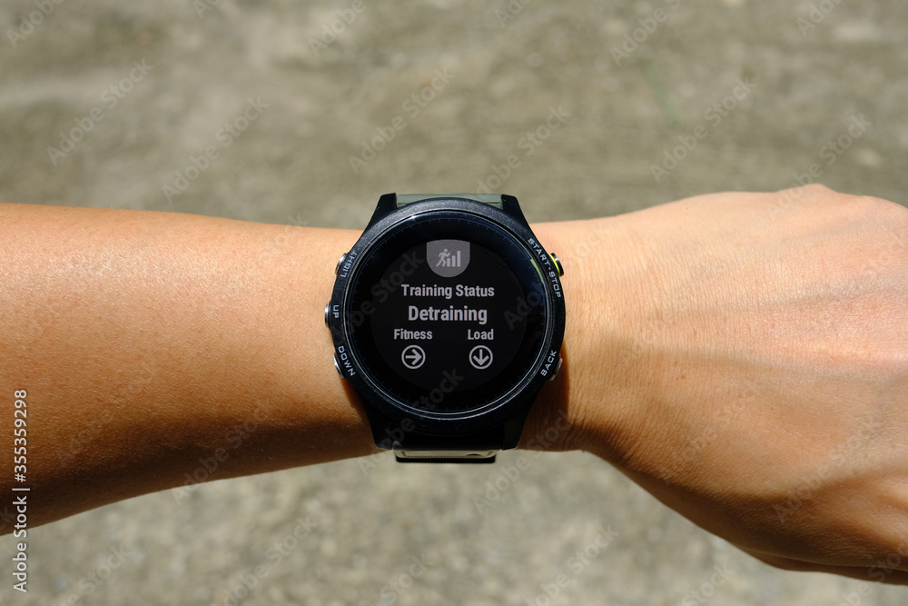 Training status on modern round-faced GPS multisport digital smartwatch on left hand wrist, detraining means decreasing load of training, selective focus. Training status on modern round-faced GPS multisport digital smartwatch on left hand wrist, detraining means decreasing load of training, selective focus.