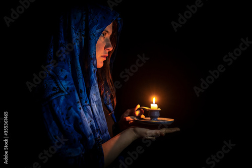 Sad young woman with candle and blue headscarf