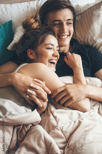 Close view photo of a happy couple lying in bed and embracing early morning