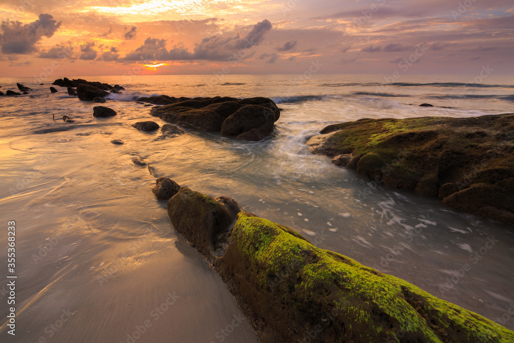 Amazing twilight Sunset seascape with sea wave hitting the green moss