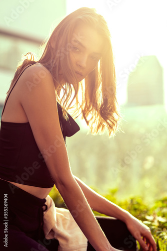 Sweet Dream. Portrait of a caucasian young woman in black casual wear looking at camera while posing outdoors. Light leak. Nature, beauty, fashion photoshoot concept. Vertical shot. Copy space