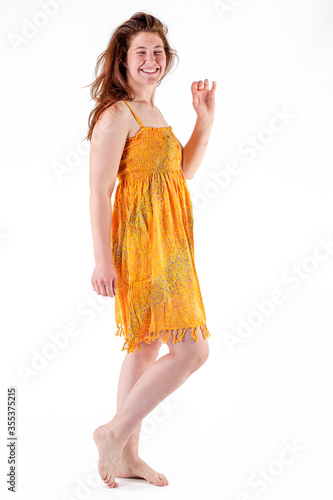 Young woman in yellow dress stands barefoot against white background