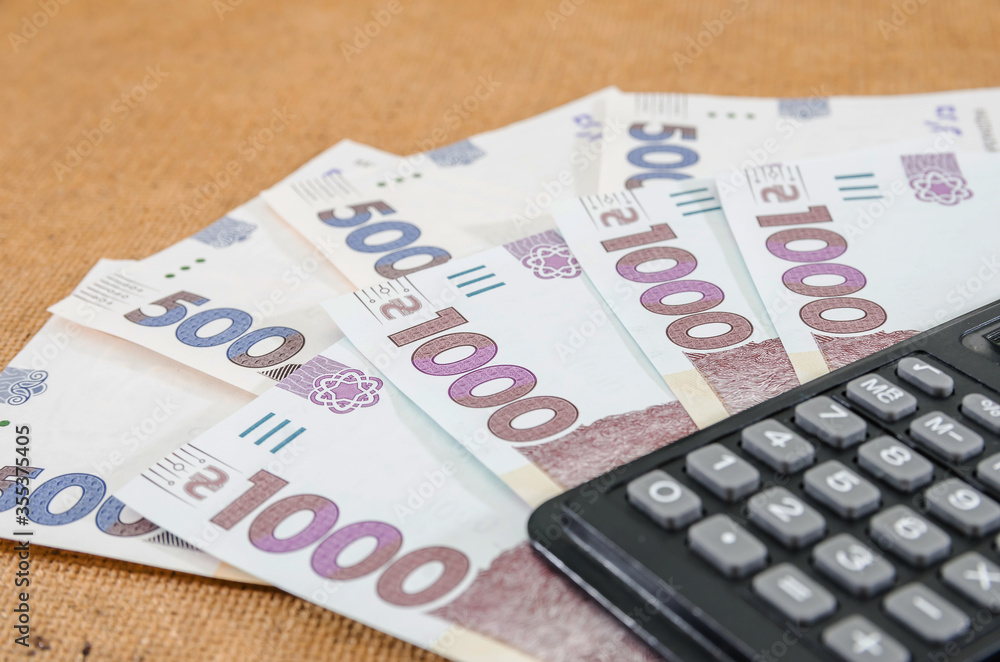1000 and 500 hryvnia with a calculator on the table. Close-up. 1000 and 500 hryvnia with a calculator on the table. Close-up.
