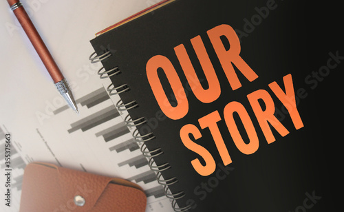 Our Stroy words written on a cover, of copybook, orange on black. Business story concept. Selective focus photo