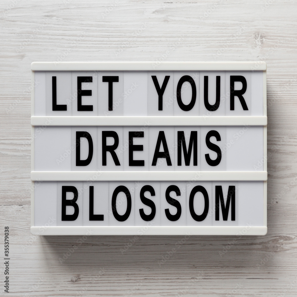 'Let your dreams blossom' on a lightbox on a white wooden background, top view. Flat lay, overhead, from above. 'Let your dreams blossom' on a lightbox on a white wooden background, top view. Flat lay, overhead, from above.