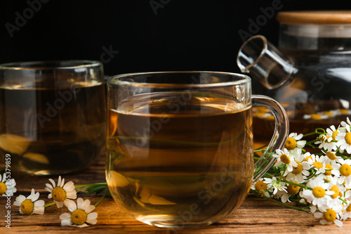 Cup of tea and chamomile flowers on wooden table