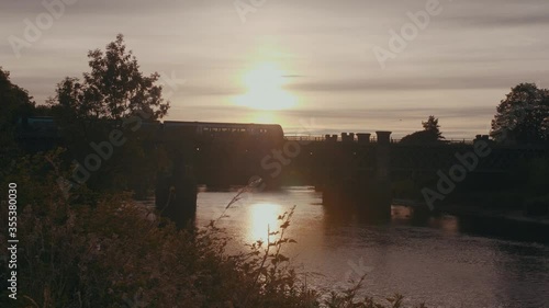 Train passing by a bridge at sunset