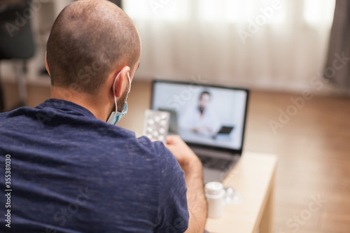 Adult man in video call with doctor talking about drug prescription during global pandemic.