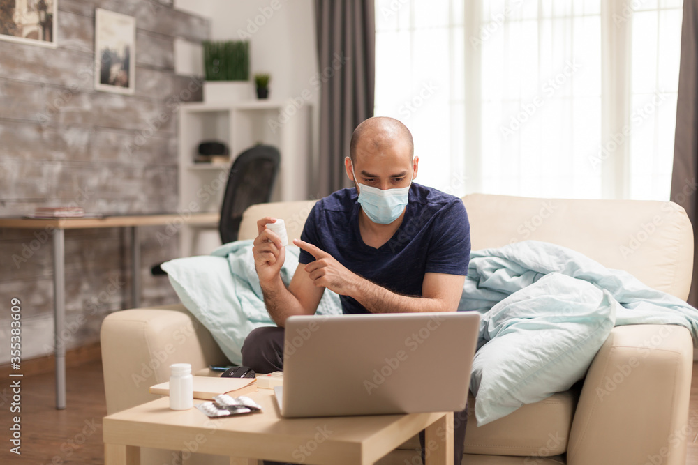 Sick man pointing at pills bottle during online consultation with his physician.