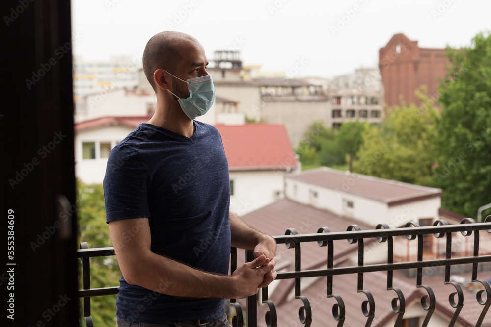 custom made wallpaper toronto digitalAdult guy with mask on balcony of his apartment during coronavirus pandemic.