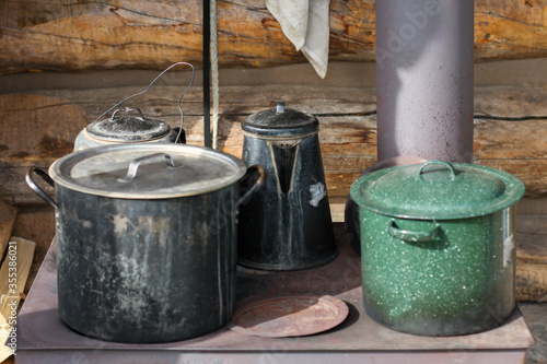 Yukon Territory, Alaska. Close up of pots and pans in an old iron cooking stove placed in the outside of a cabin.
