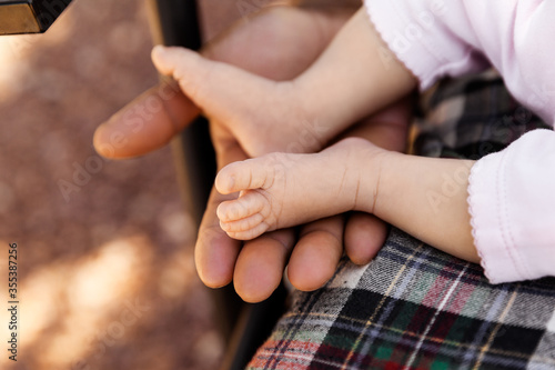 Adorable newborn baby girl feet in father’s hands, family and babyhood concept