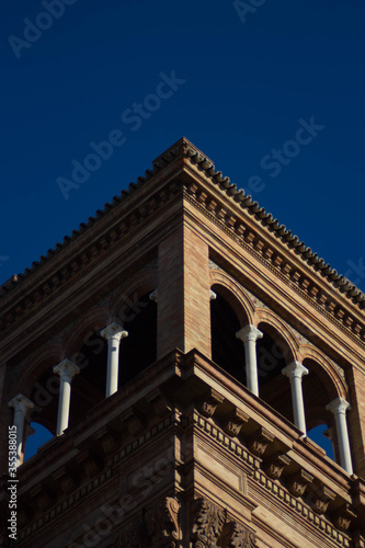 Torre de ladrillo sevillana española sombreada con cielo azul en el fondo