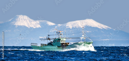 Fishing boat returns after fishing to its port. Against the backdrop of the island of Kunashir. Japan. The water area of Hokkaido. Kunashir Strait. Sea of Okhotsk.