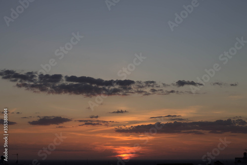 Fototapeta Naklejka Na Ścianę i Meble -  horizonte, puesta de sol con tonos cálidos, fondo oscuro, una ciudad, con nubes oscuras