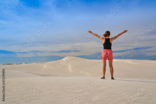 Woman walking through sandy desert dunes.