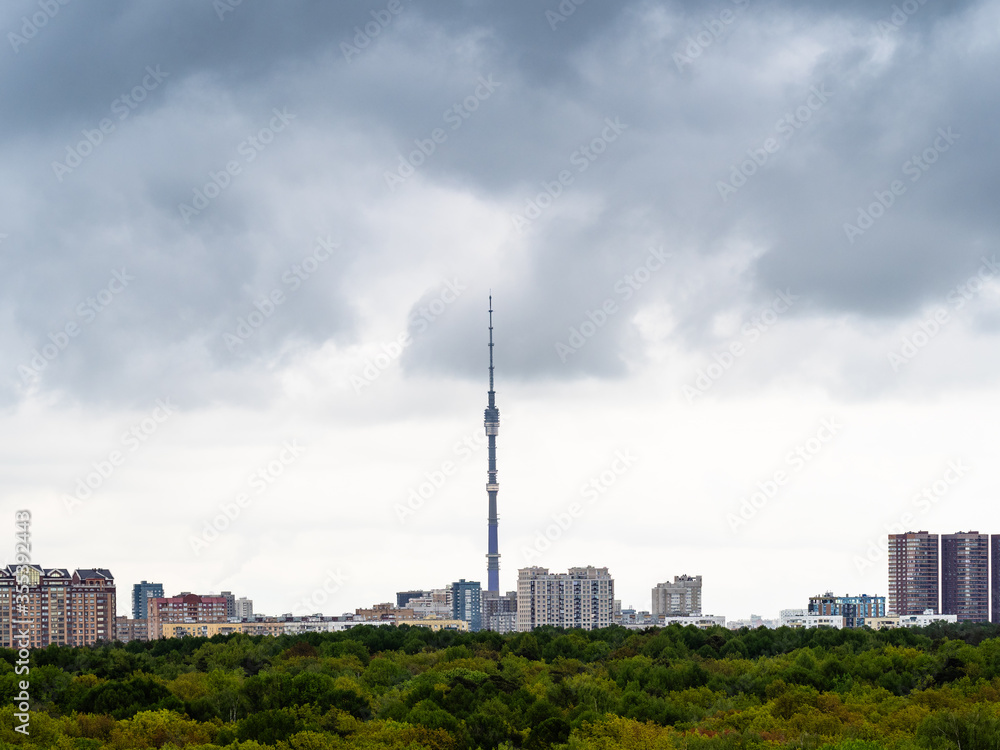 Obraz premium gray rainy clouds over residential district of Moscow city, TV tower and green park in spring