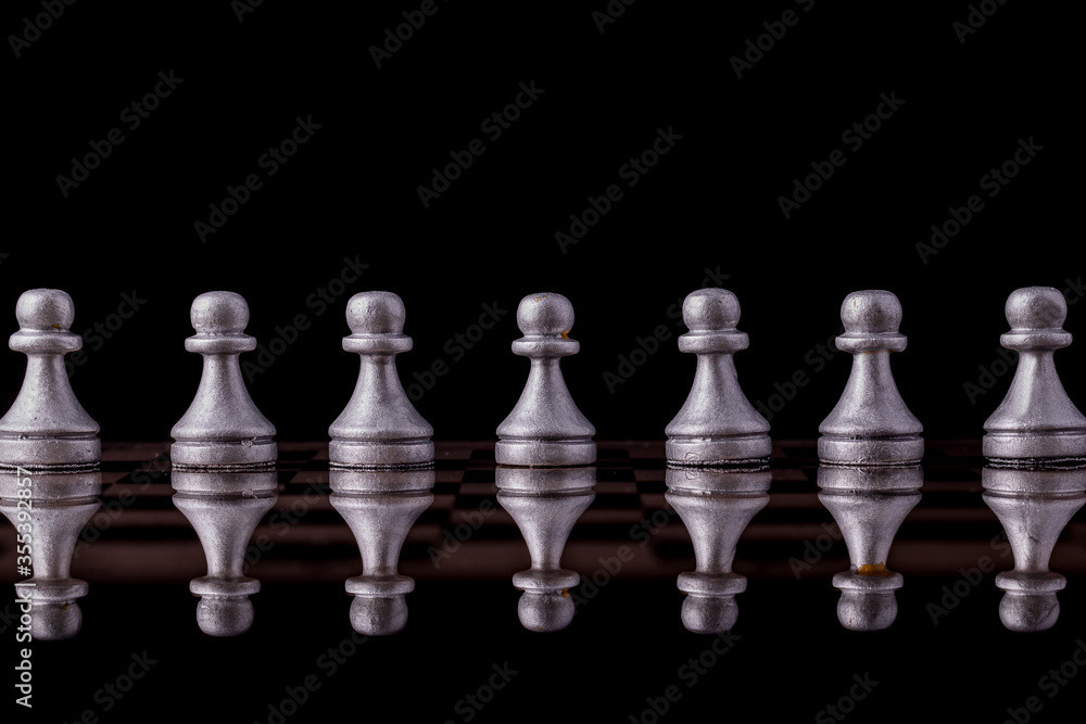 Chess pieces in silver on a black background. Board game chess. Chess pieces in silver on a black background. Board game chess.