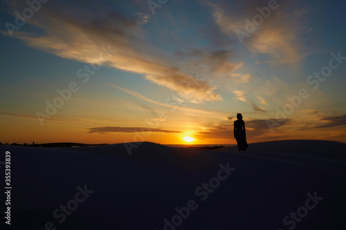 A woman standing against the backdrop of the setting sun © Damian
