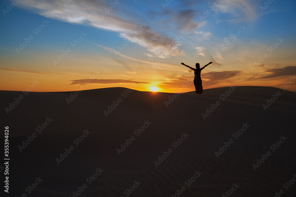 A woman standing against the backdrop of the setting sun